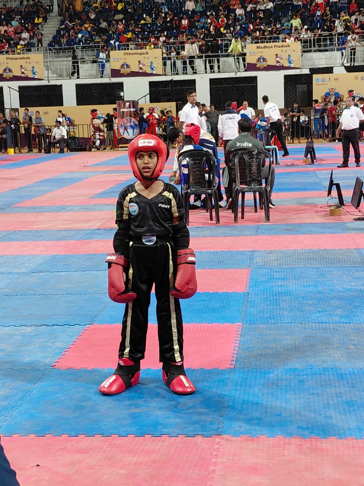 Rakshathra in fight gear at a packed national-level kickboxing stadium