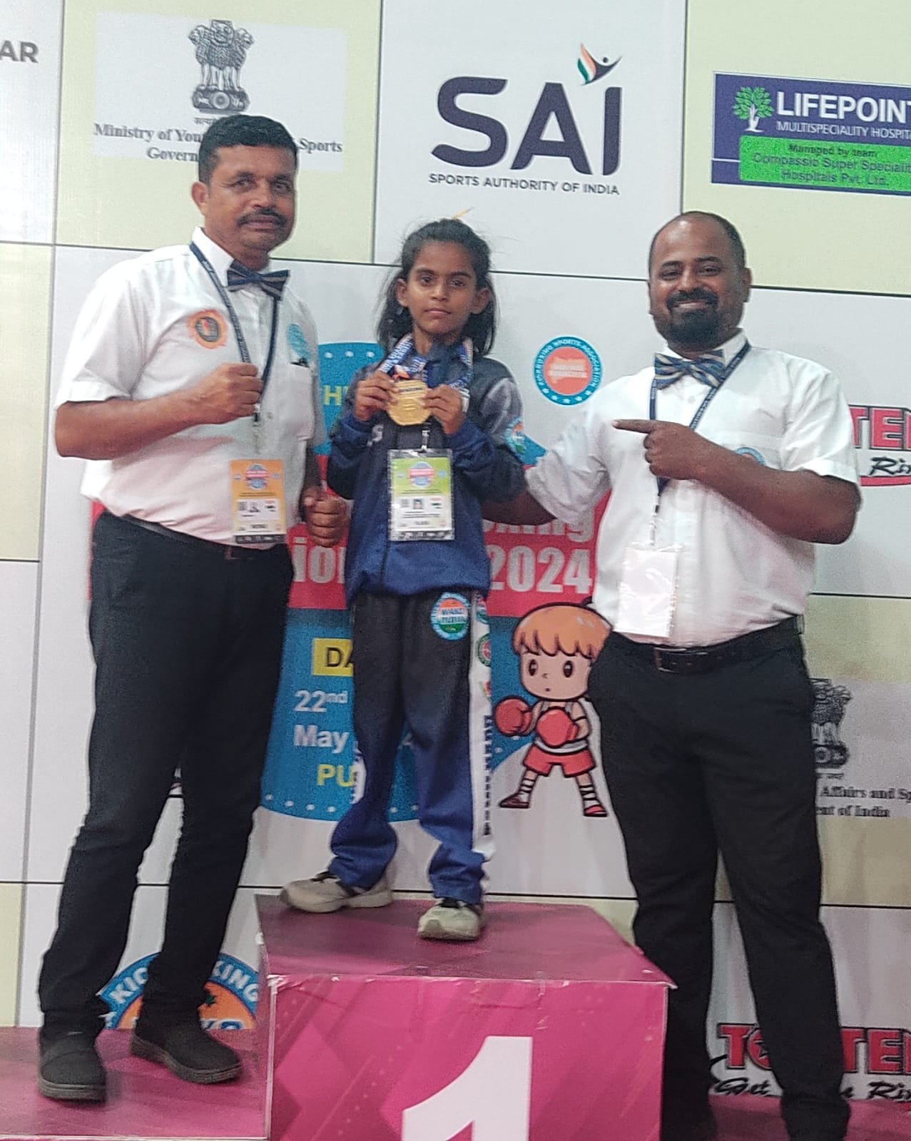 Rakshathra on the 1st place podium at a national kickboxing championship, Pune, May 2024, with Sports Authority of India officials