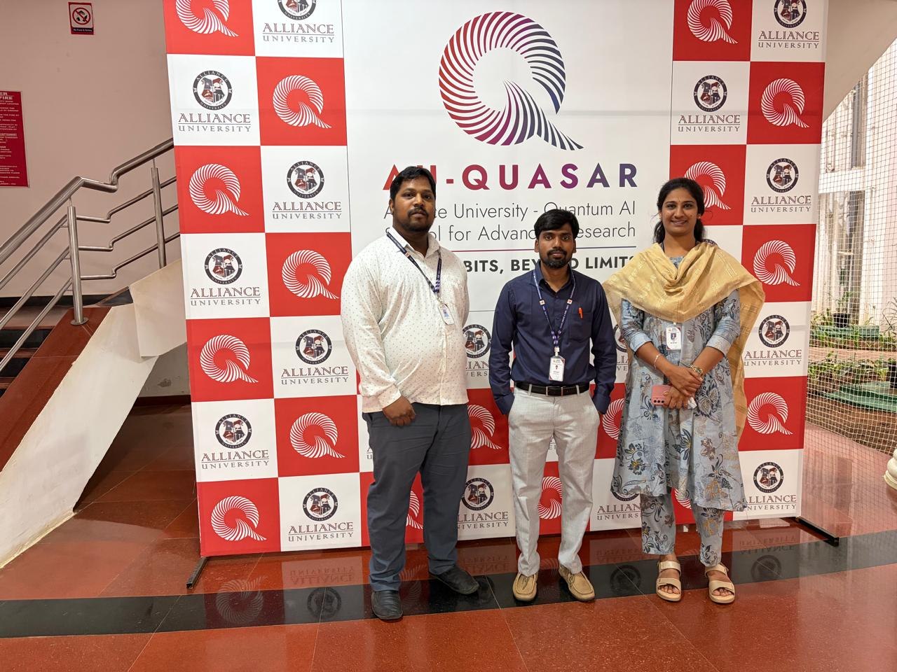 Mr. Prabakaran M, Tr. Samson and Tr. Nithya at the AU-QUASAR backdrop, Alliance University