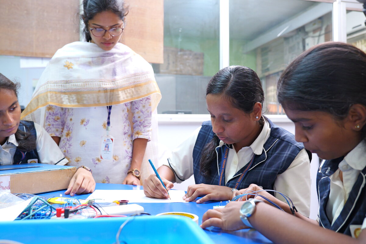 A teacher and students sketching out the circuit design on paper before building