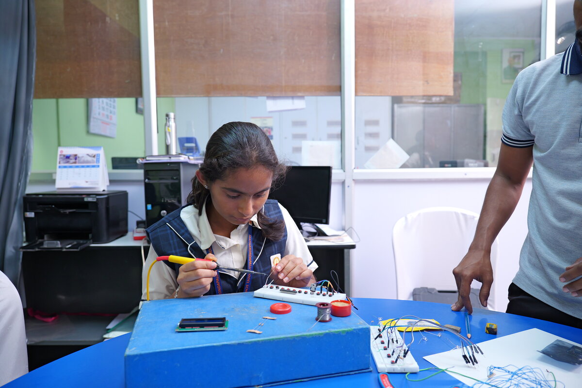 A student soldering wire connections onto the breadboard