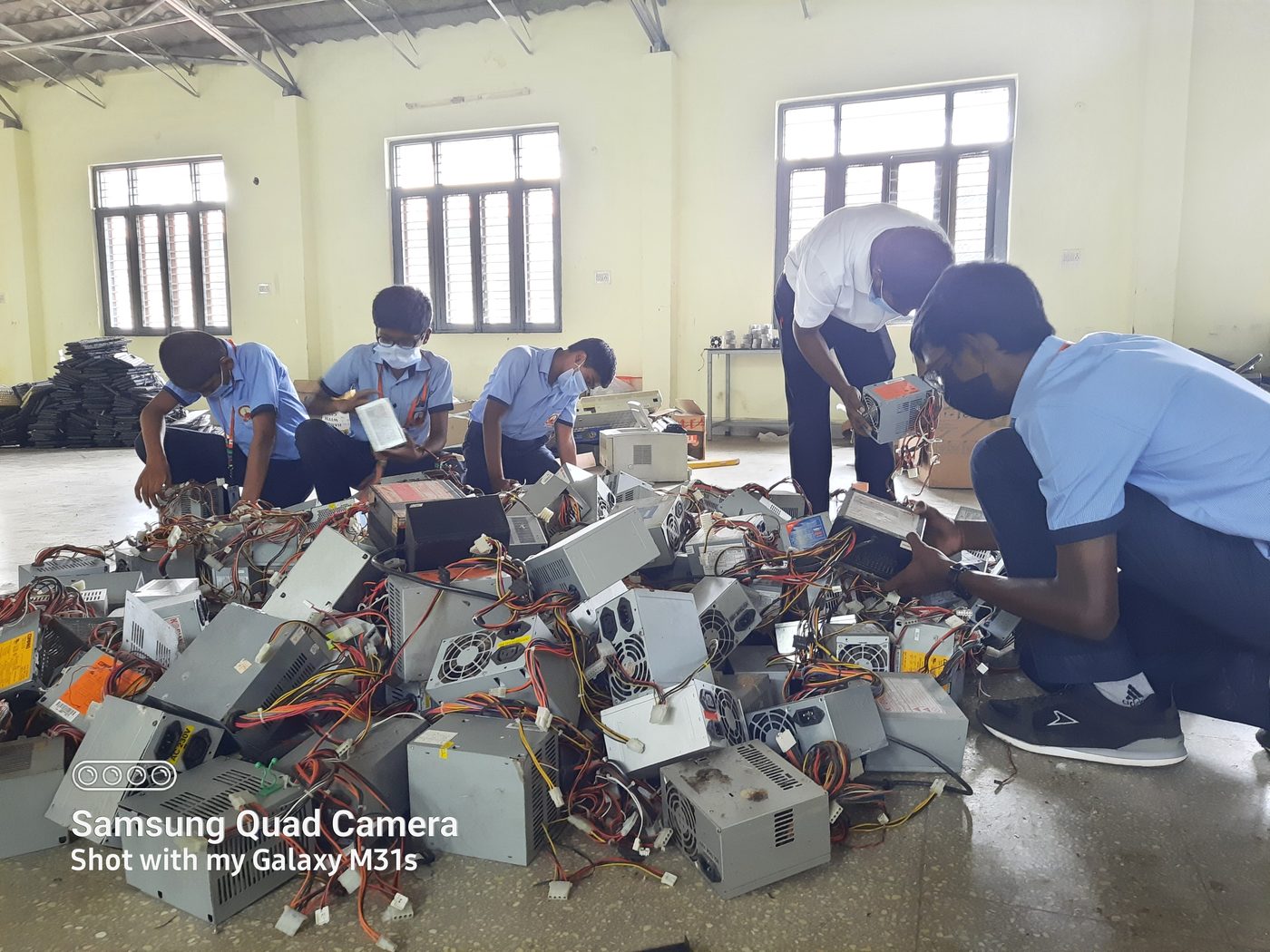 Students and staff disassembling computer power supply units to salvage wiring and components