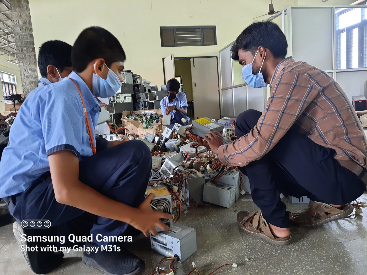 Students and a staff member disassembling power supply units together