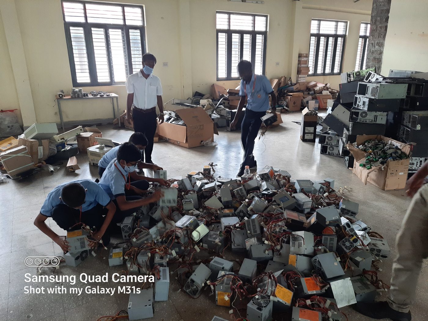 Staff and students sorting through a large pile of power supply units