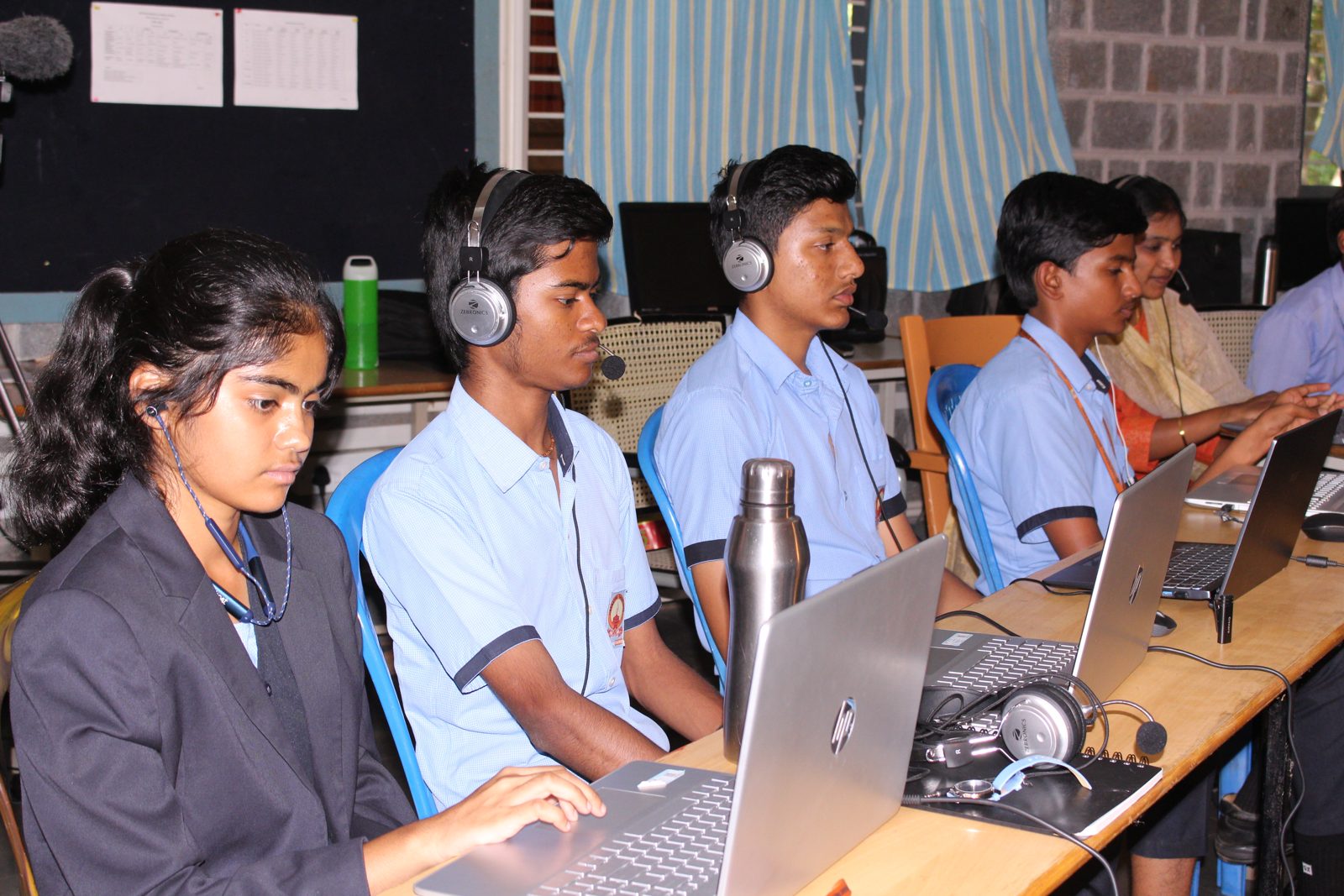 Students with headsets listening closely to the session, with laptops in front of them
