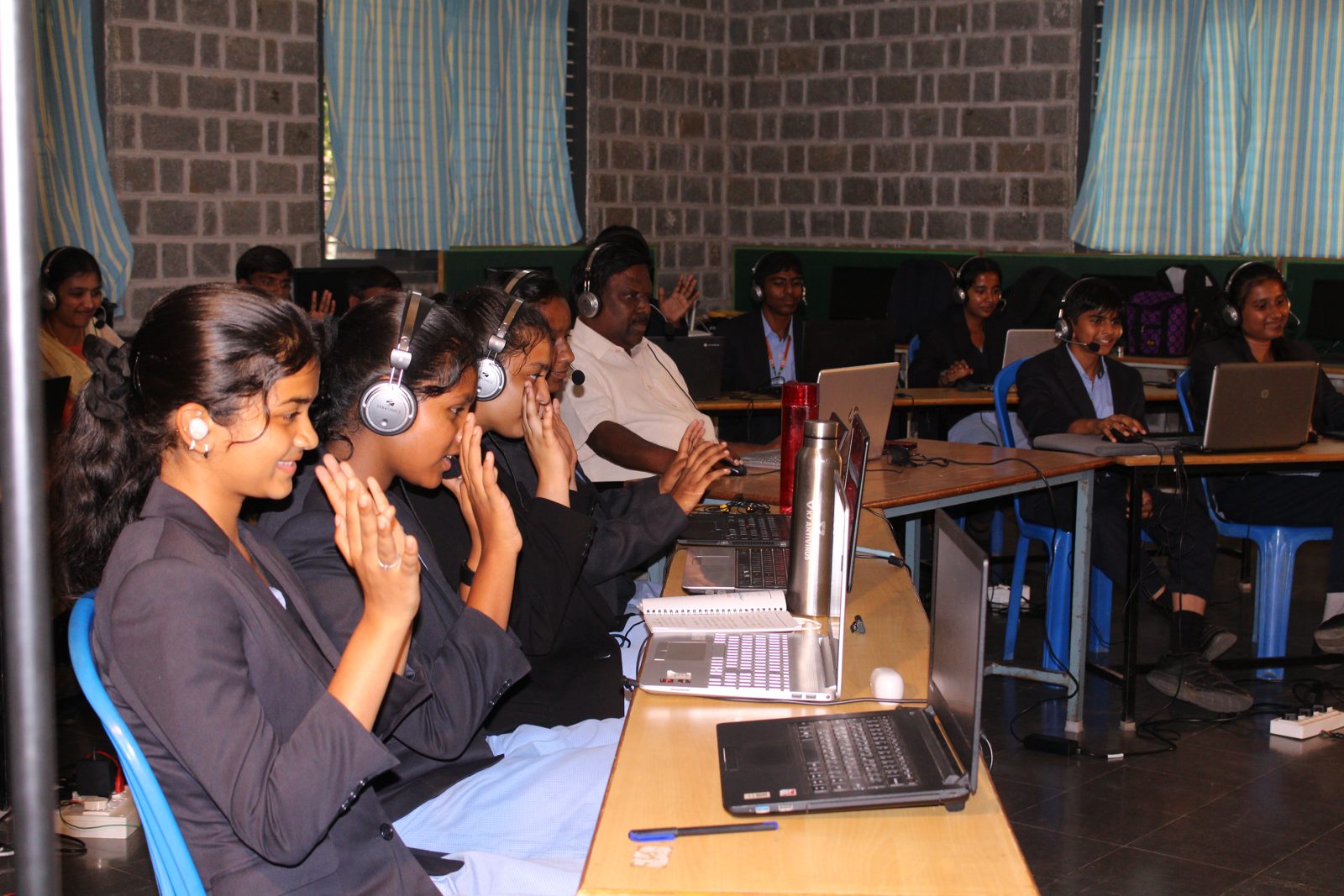 Students with headsets smiling and applauding during the live session