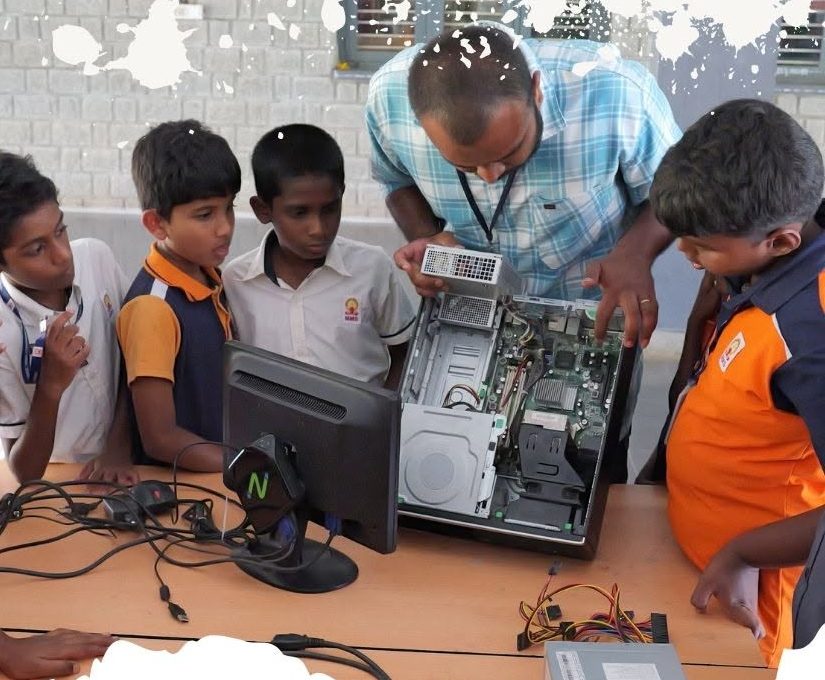 Students examining a disassembled desktop computer with their teacher