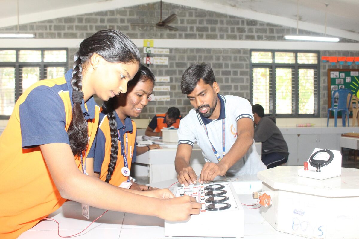 A student and staff member studying a physics circuit apparatus together