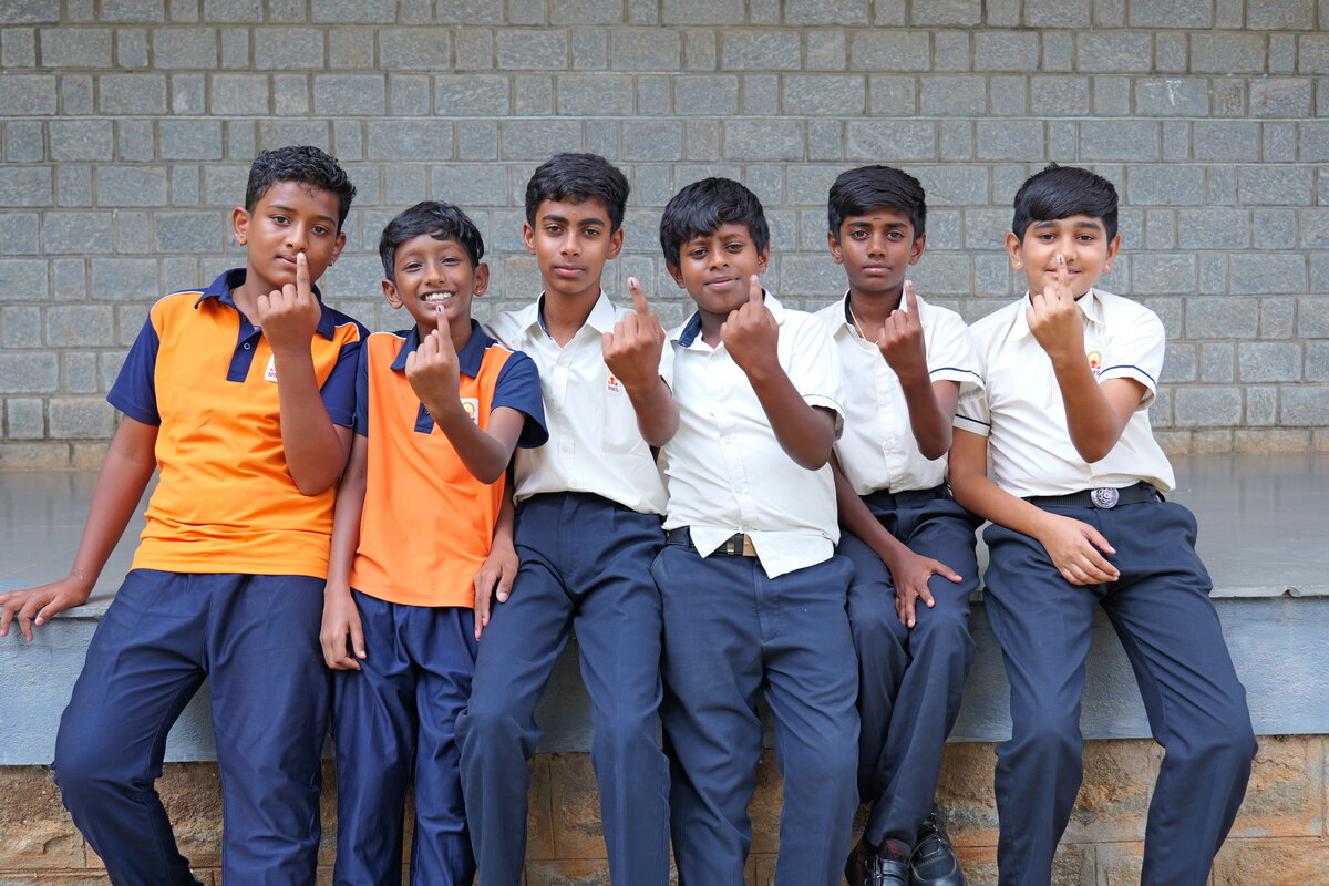 Six students proudly showing their ink marked fingers after voting