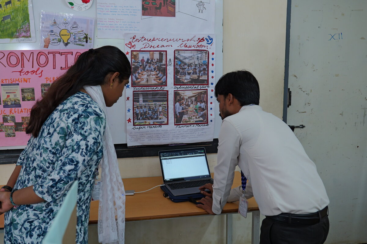 Teachers cross-checking the vote count on a laptop next to the SEVS machine