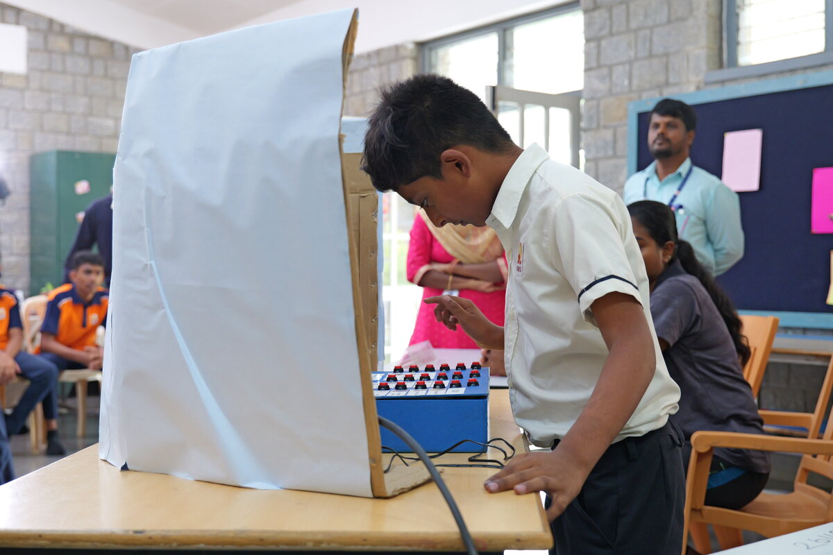 Close-up of a student pressing a button to cast their vote on the SEVS machine