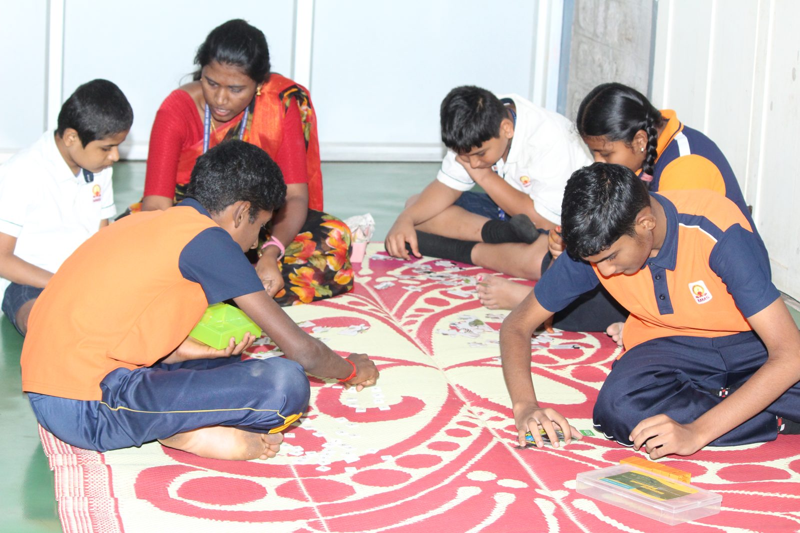 An educator and students sitting on a floor mat doing a card activity