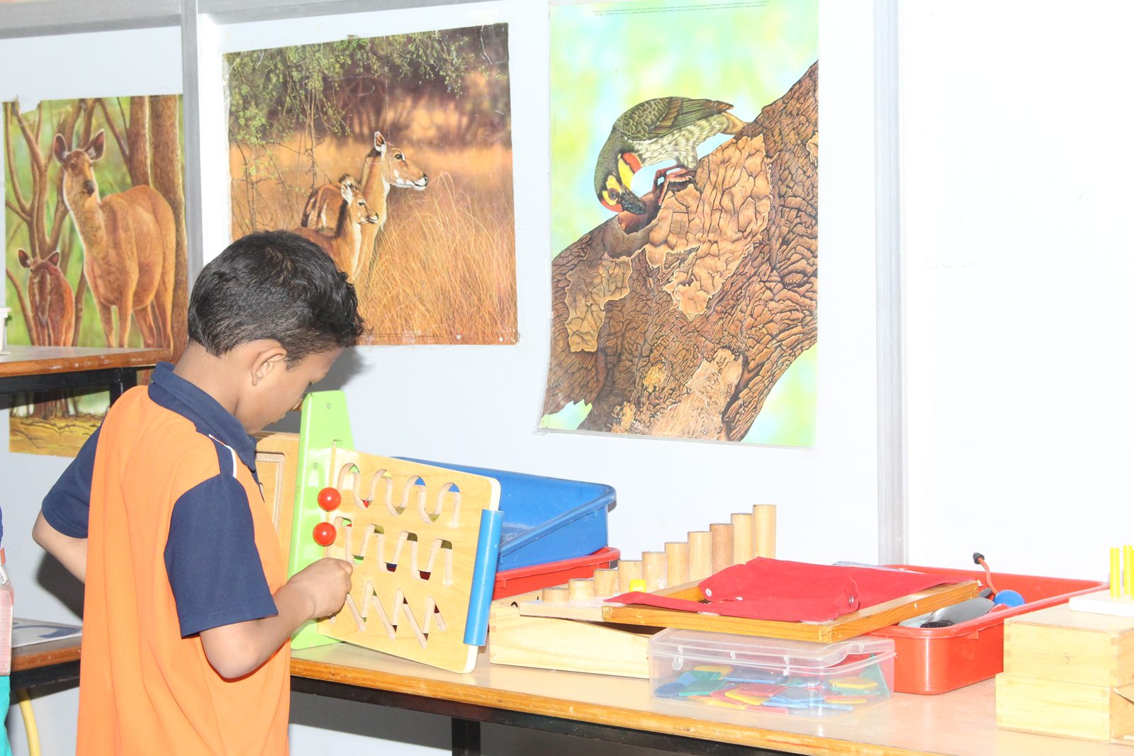 A student working with a wall-mounted peg board and learning materials