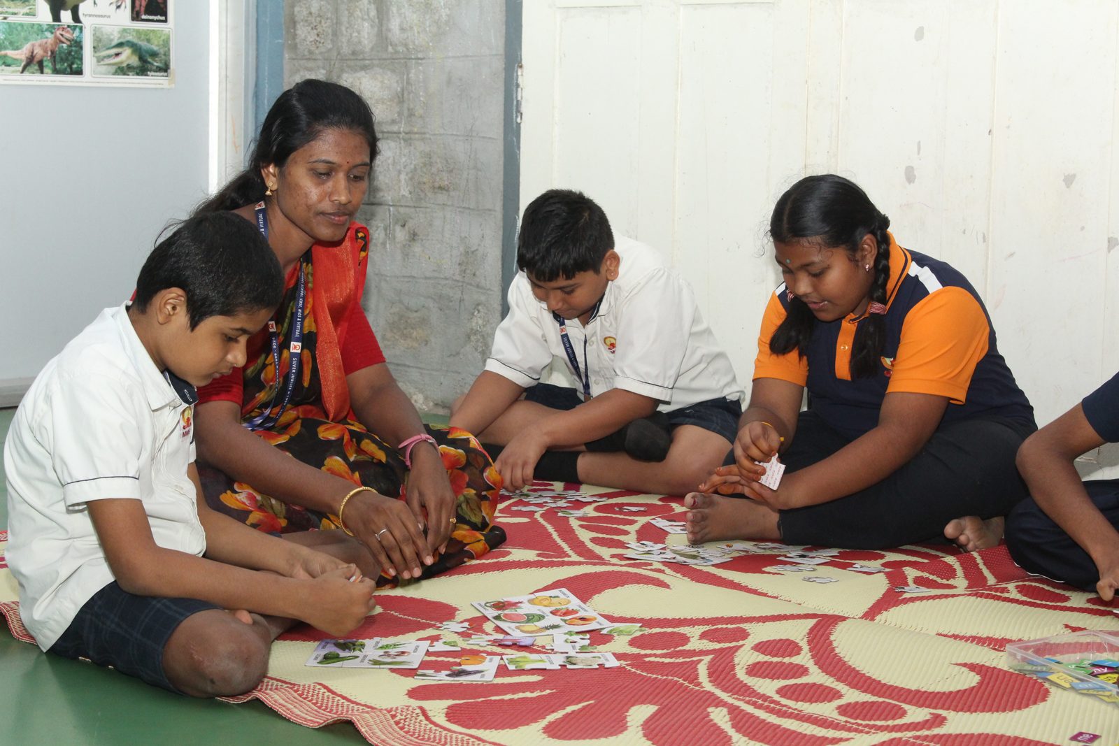 Students and an educator playing a picture card game on a floor mat