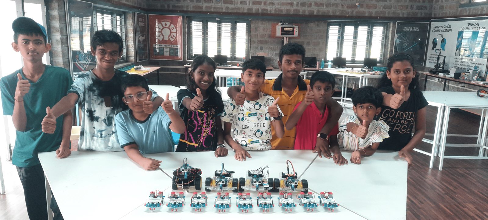 Students with their finished robots, giving a thumbs up